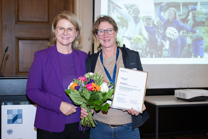 Sabine Porschmann, Parlamentarische Staatssekretärin bei der Bundesministerin für Wohnen, Stadtentwicklung und Bauwesen, übereicht Kerstin Mommsen, VAUDE Unternehmenskommunikation, den Bundespreis. (Foto: © BBR/BBSR/bundesfoto/BA) 