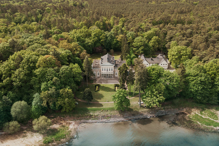 Drohenenansicht auf das Schloss Manowce, man sieht das Haus und den See davor