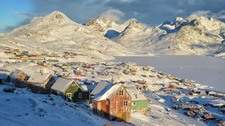 Vinter i Tasiilaq. Kong Oscar Fjord er frosset til og dækket af sne. Solen skinner. De farverige huse i rødt, blåt, gult og grønt er farvestænk i det hvide vinterlandskab.