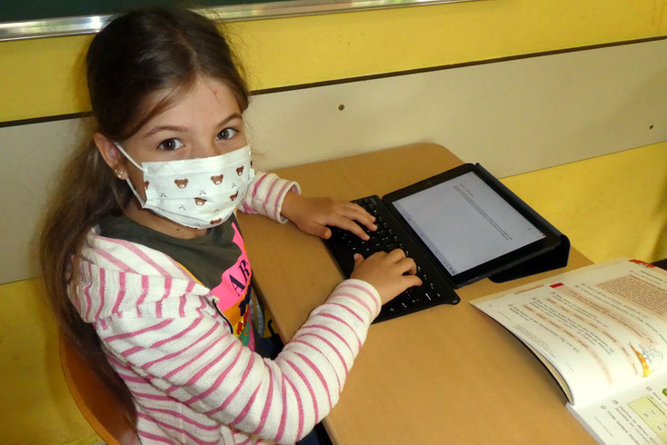 Viertklässlerin Melissa nutzt iPad und Tastatur für das Abtippen eines Textes 