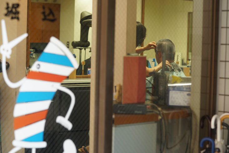 理髪店。中では整髪されている男性。