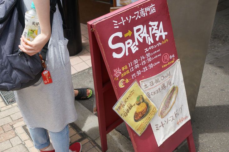 ミートソース専門店スペランツァの置き看板。布に描かれた食べ歩き専用ミートソースドックが貼られている。
