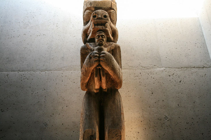 Die Bärenfigur hält den Menschen beschützend in seinen Armen. Die Figur war ursprünglich ein Hauspfosten.
