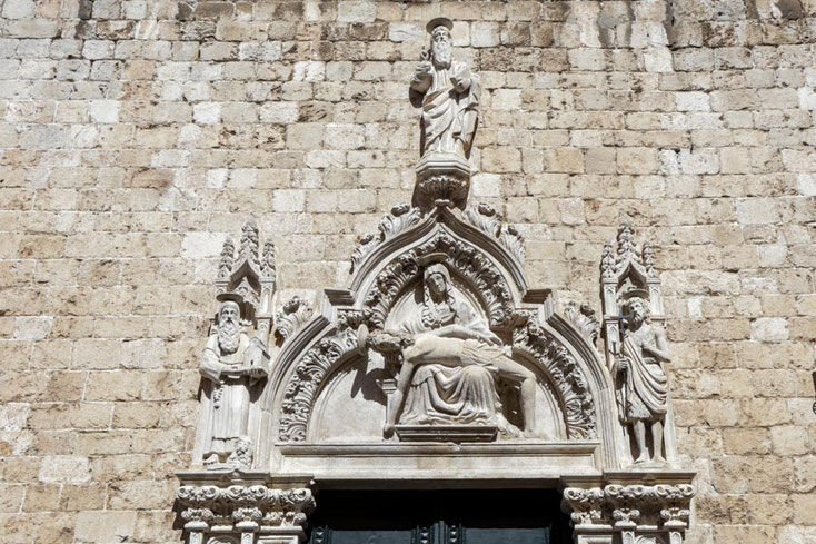Tympanon über dem Portal der Kirche des Franziskaner-Klosters mit Maria, die den Leib Jesu hält. Links ist der Heilige Hieronymus, rechts Johannes der Täufer dargestellt.