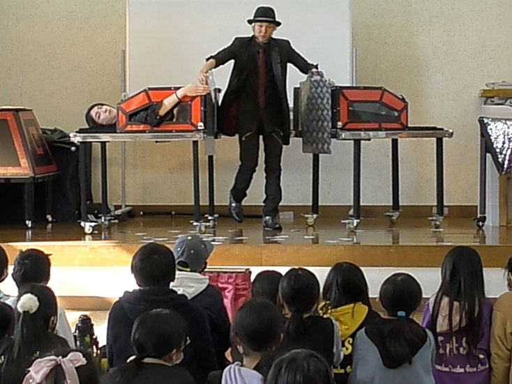 何台かのイリュージョン道具の前にいるマジシャンRYUHEI