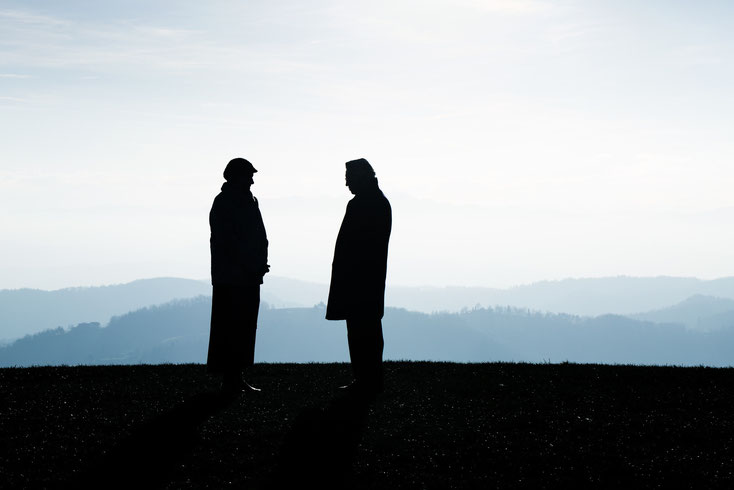 Die Silhouetten zweier Männer, die sich auf einer Anhöhe gegenüberstehen; Detektive der Kurtz Detektei Hamburg