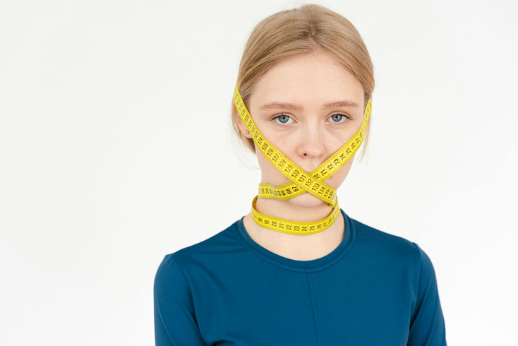 Foto: Junge Frau mit einem Messband, das um ihr Gesicht geschlungen ist