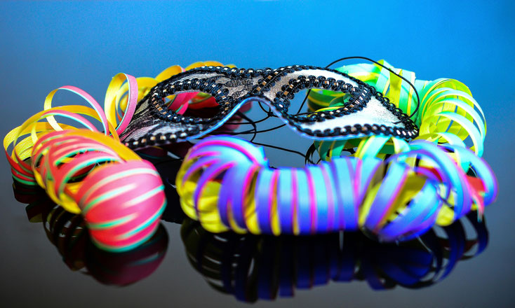 Bild von Faschingsdekoration: Eine Maske und bunte Papierröllchen