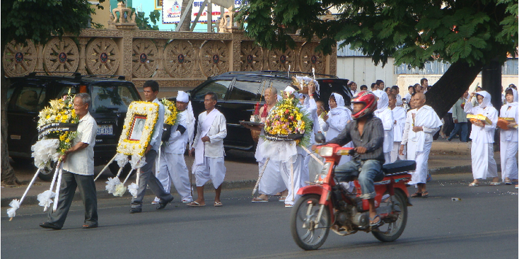 Phnom-Penh-ceremonie-bloemen-straatleven-scooter-straat-mondkapje-Cambodja