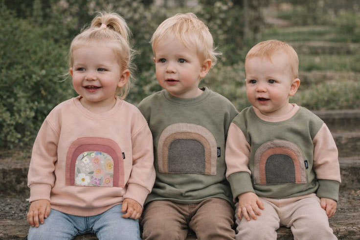 Drei Kinder in Regenbogen-Pullovern - Babykleider und Kinderkleider Kollektion | Scherzinger-Baby