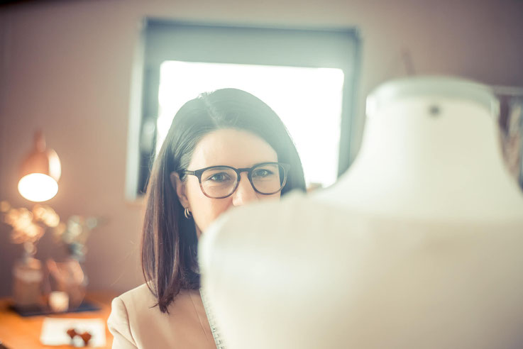 Designerin mit Schneiderpuppe in ihrem Atelier und Schneiderei beim anfertigen eine maßgeschneiderten Brautkleides