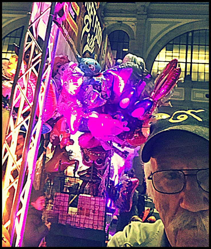 Pedro Meier Unterwegs in der Bahnhofshalle Zürich HB, Food Festival, mehrfarbige Luftballons: Delfine, Heuschrecken, Einhörner, Schmetterlinge, Libellen, Krokodile, Der Reisende und die Metamorphose in seinem Element, untermalt mit wilder Musik, 2025