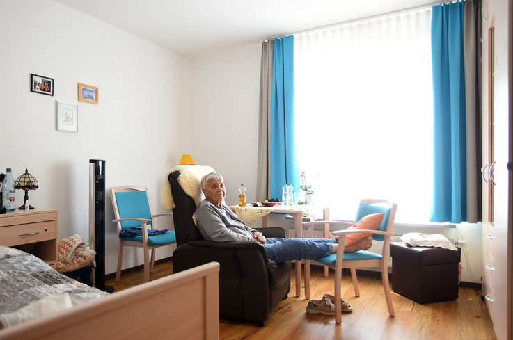 Eine Heimbewohnerin liegt entspannt  in ihrem Sessel von zu Hause und ruht in sich