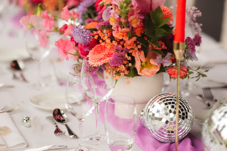Décoration de mariage à Lille et dans les Hauts-de-France avec centre de table fleuri coloré, bougies rouges et boules disco
