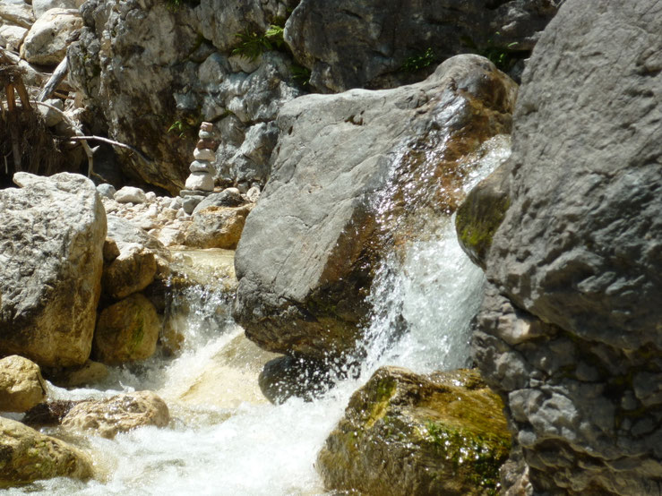 Belebtes Wasser in einem Gebirgsbach mit einem Gebilde aus aufeinandergestellten Steinen / Stoanamandl dahinter in Bad Reichenhall / Berchtesgadener Land - Heilpraktiker Martin Johannes Gahbauer