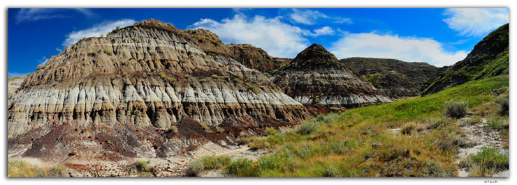 Horseshoe Canyon in Canada near Drumheller shows various earth layers and a blue sky with clouds.