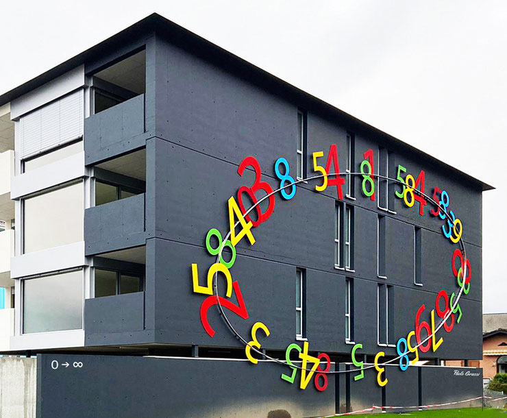 Paolo Grassi’s public installation Les Deux Roses in Cadenazzo, featuring a red numerical sculpture on grass near a transit road.