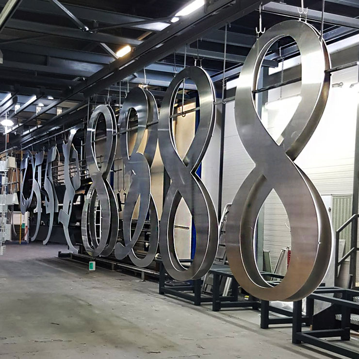 Large metal numbers for “Fortis” hanging in the workshop, awaiting color and installation.