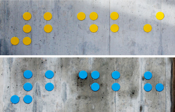 Close-up of yellow and blue Braille compositions on a concrete wall / Dettaglio di composizioni Braille in giallo e blu su una parete in cemento