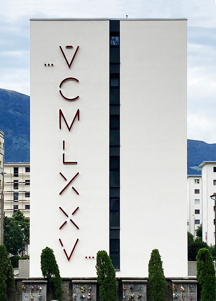 Full frontal view of the VCMLXXV vertical Roman numeral installation by Paolo Grassi, spanning the entire facade.