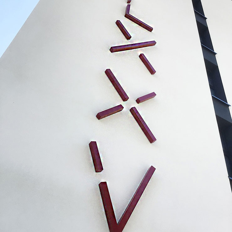 Upward close-up of red Roman numerals from Paolo Grassi’s VCMLXXV installation on a building wall in Locarno.