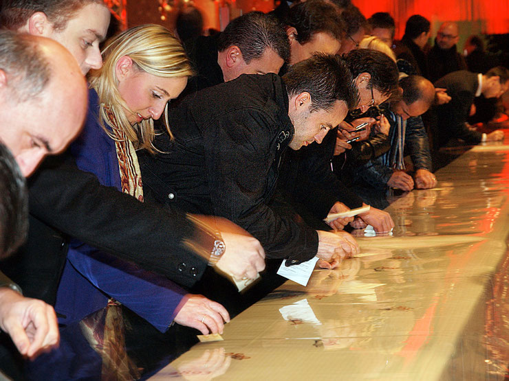 Group of participants signing unique numbers during Paolo Grassi’s large-scale participatory installation at UBS SA – From '0' to Infinity