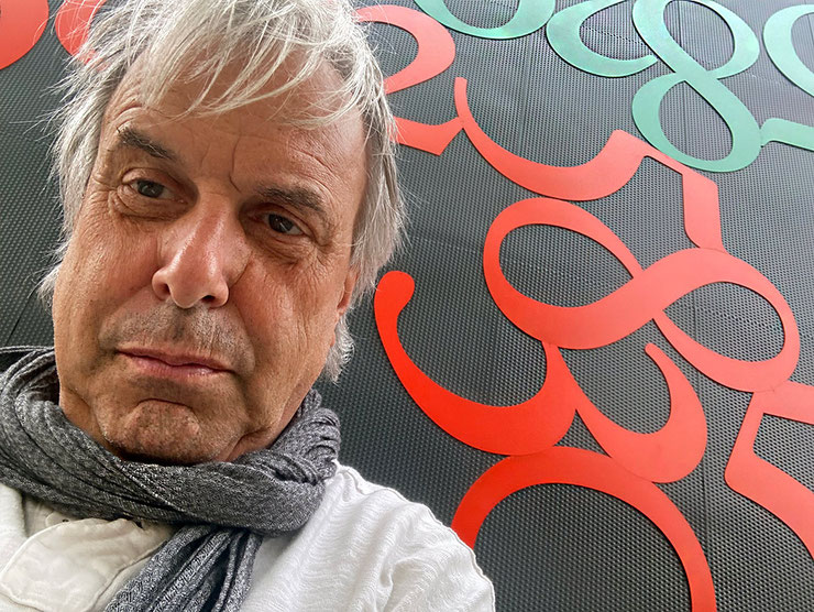 Portrait of Paolo Grassi in front of “Fortis”, surrounded by sculptural red and green numbers.
