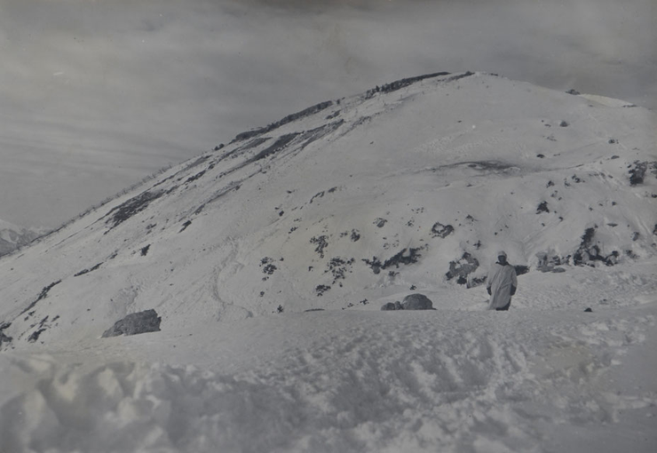 Ein Gebirgsschütze vor der verschneiten Cukla. Die Spuren im Schnee zwischen der alten Österreich-Ungarischen Linie und der eroberten italienischen Line auf der Cukla datieren das Bild auf die Zeit nach der Einnahme des Gipfels. Sammlung Isonofront.de