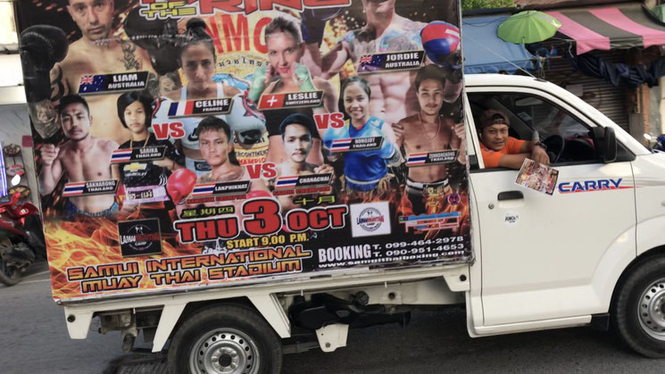 Ein Pick-Up mit Werbeplakaten für eine Muay Thai-Wettkampfveranstaltung.