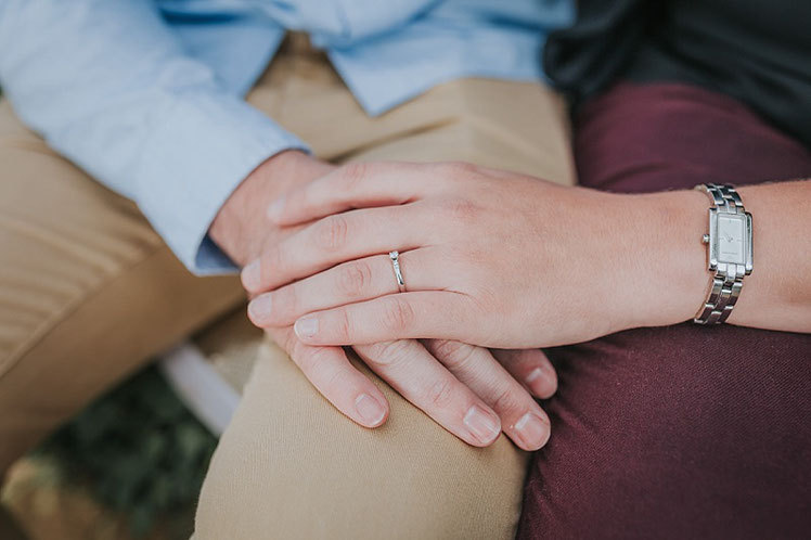 A couple holding hands showing off her engagement ring