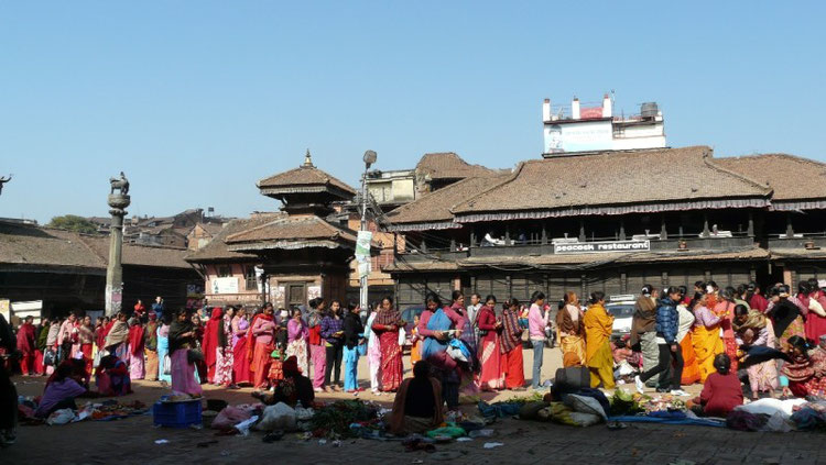 Longue queue au temple principal de Bakthapur (une des trois villes royales de la vallee de Kathmandou). Drapees dans leur saris colores les femmes viennent deposer leur offrandes (fruits, oeufs, fleurs, bougies..)