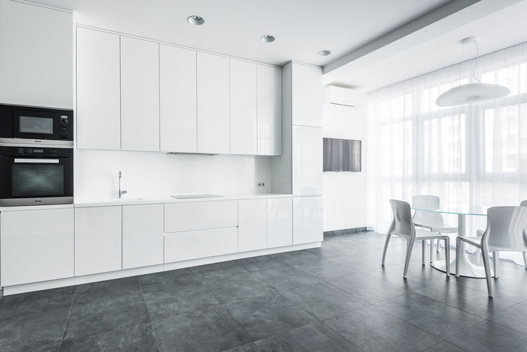 high gloss white kitchen finger pull style with large floor tiles and white dining chairs