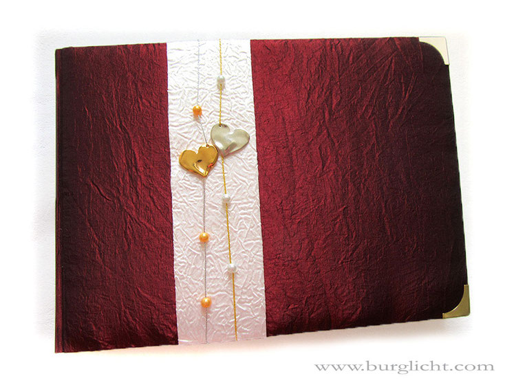 Hochzeitsalbum, Hardcover gepolstert, Crashtaft bordeauxfarben, Herzanhänger silber und gold; Perlen, Kordeln und Buchecken silber- und goldfarben; 35cm x 25cm x 5cm Querformat, 100 Seiten elfenbeinfarben.