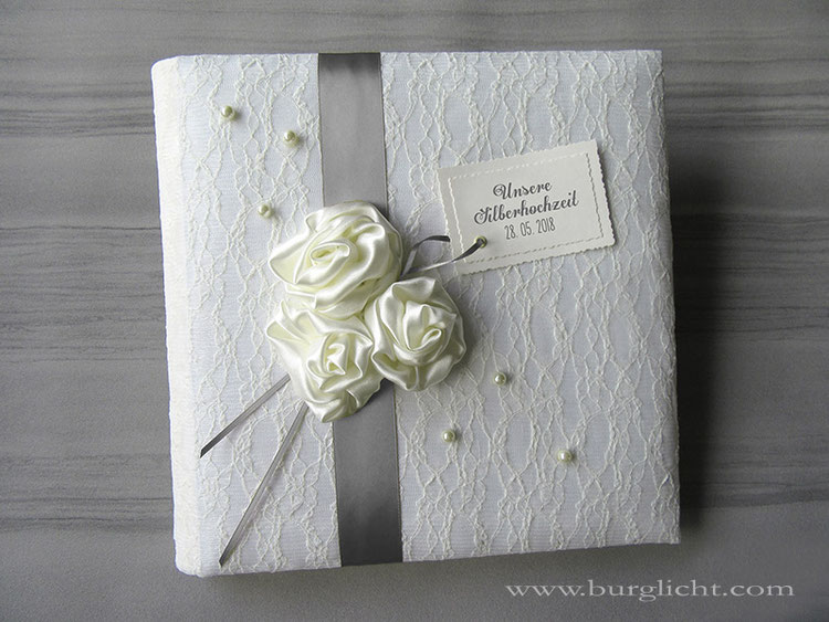Fotoalbum zur Silberhochzeit, Hardcover gepolstert, Bucheinbandmaterial Stoff Spitze/Lingerie naturweiß, voluminöse Satinrosen handgenäht, Zierperlen, Karton-Label bedruckt, 30cmx30cm, 50 Blatt Off-White.