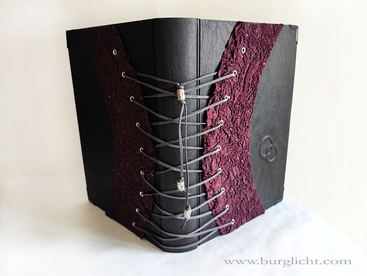 Gästebuch Hochzeit, Korsett, Ringe, Stoff schwarz und bordeauxfarben, 22cm x 31 cm, 100 Seiten Büttenpapier, Bezug: Crash-Stoff schwarz, Korsett: bordeauxfarbener Crash-Stoff mit Pailletten, anthrazitfarbene Kordel, silberfarbene Hohlnieten.