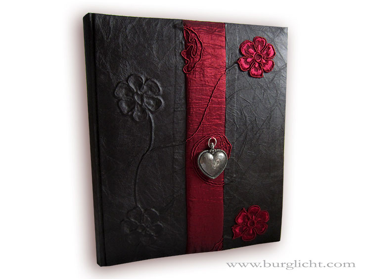 Erinnerungsalbum, Stoff schwarz, Borte und Blumen-Applikationen rot, Herzanhänger altsilberfarben, 29cm x 32cm Hochformat.