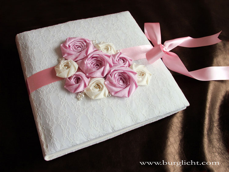 Romantisches Fotoalbum zur Hochzeit, 30cmx30cm, 100 Seiten, Bezugstoff Lingerie (Spitze) naturweiß, Einbanddekoration: Stoffrosen, Perlen und umlaufenden Schleifenverschluss in den Farben creme, rosa, pink; Druck persönlicher Daten im Inneren des Albums.