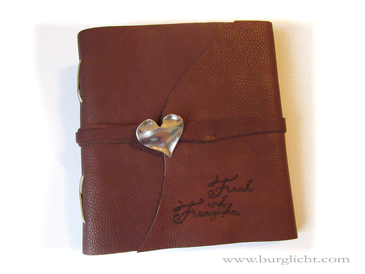 Lederbuch, Dickleder braun, Softcover mit Überschlag, Kreuzstichbindung, umlaufender Lederriemen mit Herzanhänger als Buchverschluss, Lederbranding Namen.
