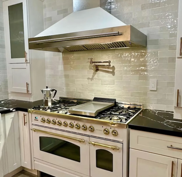 a modern pot filler installed above the kitchen cooktop with a long jointed swing out arm