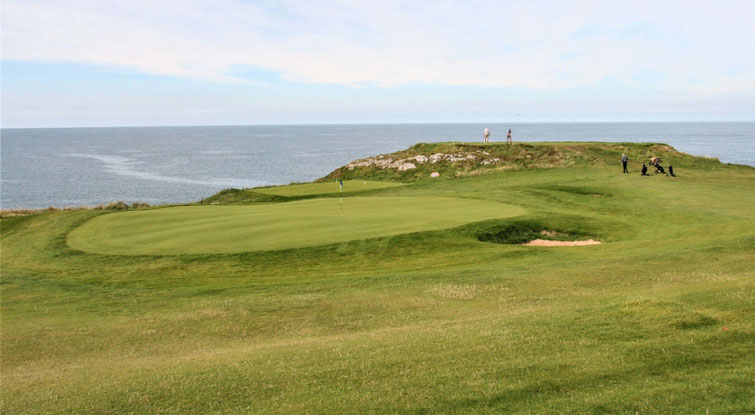 Putting Green des Nefyn Golfplatzes in Wales im Vorgergrund, im Hintergrund das Meer