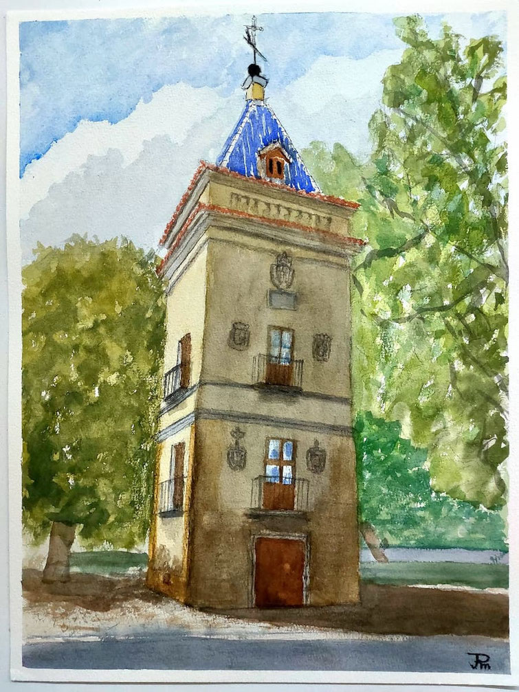 Torre alta con tejado azul y veleta, balcones de hierro y escudos en la fachada, rodeada de árboles bajo un cielo claro.