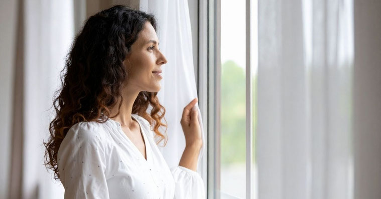 Frau am Fenster reflektiert über innere Leere füllen durch Innenschau