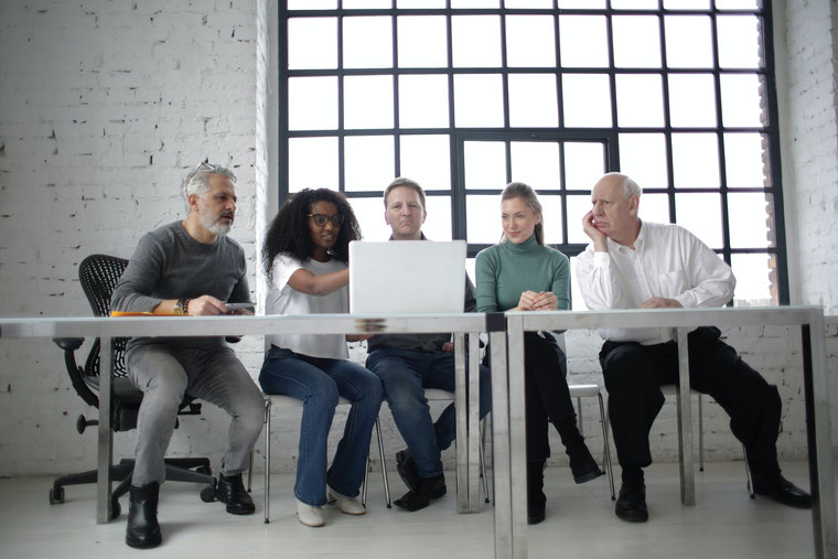 Eine Gruppe aus zwei Frauen und drei Männern beraten sich beim Block auf einen Laptop. Foto von Andrea Piacquadio auf Pexels.