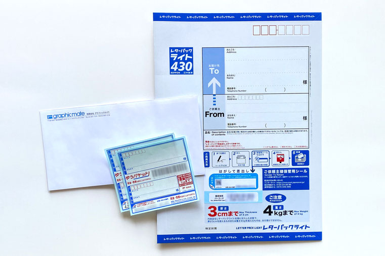 左側にグラフィックメイトの長3封筒があり、ゆうパケットの専用宛名シール2枚が重ねて置いてある。右側にはレターパックライト