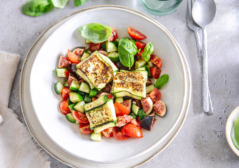 Gebratene Zucchini-Feta-Taschen auf mediterranem Salat mit Gurke, Kirschtomaten, Feige und Basilikum, verfeinert mit Olivenöl-Balsamico-Dressing.