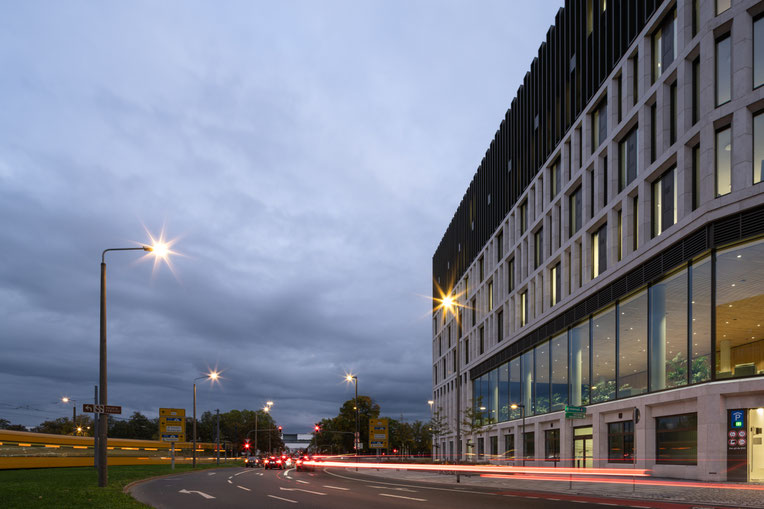Exterieur, met avondlicht en passerende auto's, van het Stadtforum Dresden, ontworpen door Barcode Architects en Tchoban Voss Architekten