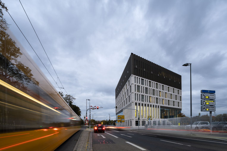 Exterieur, met avondlicht en passerende tram van het Stadtforum Dresden, ontworpen door Barcode Architects en Tchoban Voss Architekten