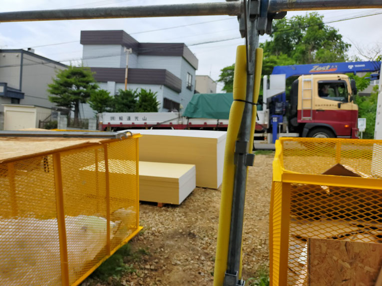 住宅の外に石膏ボードが複数枚、平積みされている様子。