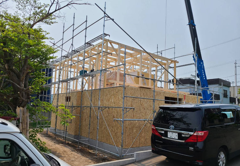 現場に設置されたクレーン車と作業風景。建物の上棟に向けて重要な作業段階。