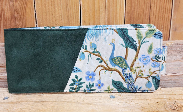 porte-chéquier horizontal femme souche à gauche, patte de fermeture suédine vert bouteille, tissu blanc cassé avec des fleurs et des paons, porte-chéquier chic et élégant fabriqué artisanalement en France